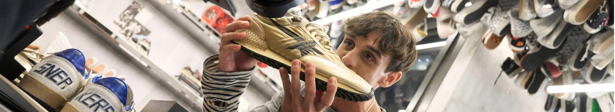 cory-jounou-with-marathon-gold-sneaker-in-hand-surrounded-by-shoes