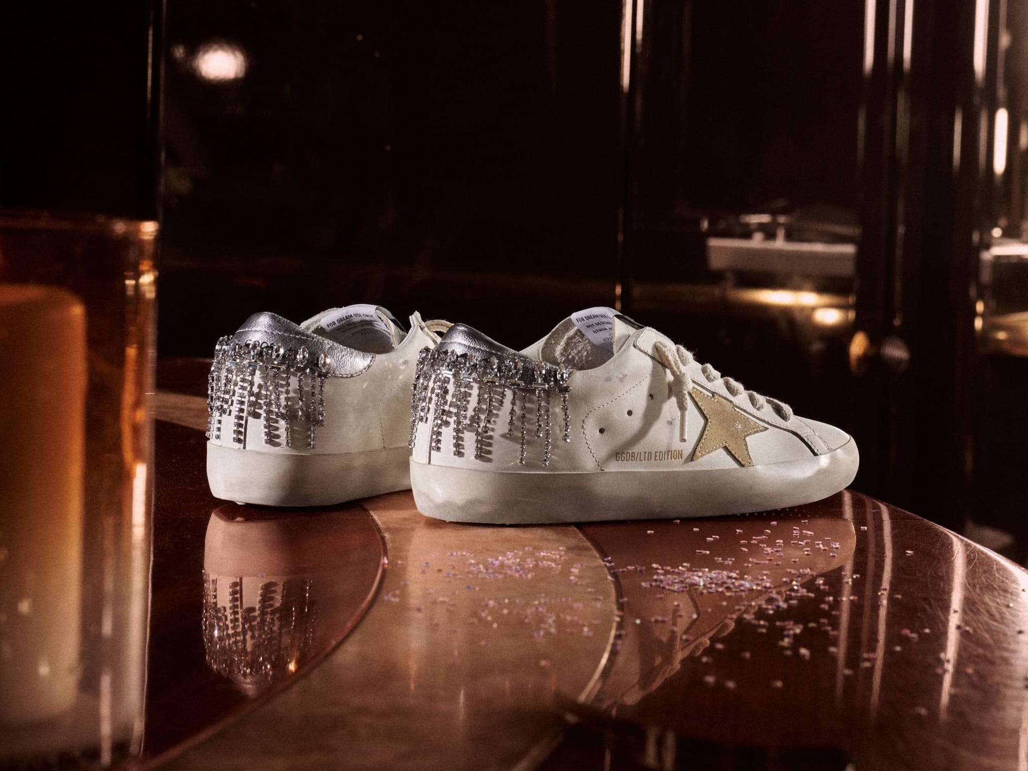 white-super-star-sneakers-with-shiny-details-on-heel-on-top-of-bronze-table