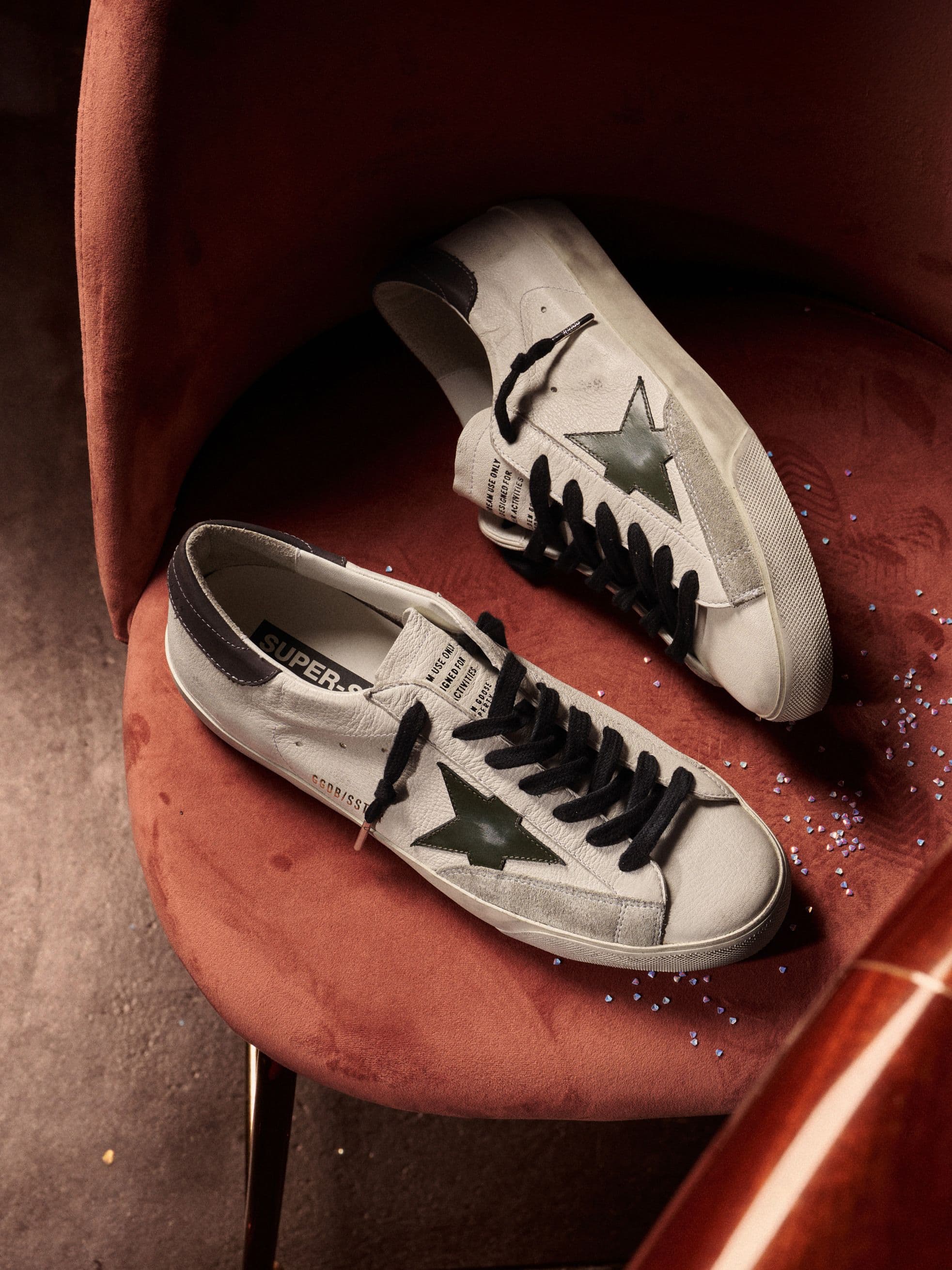 white-super-star-sneakers-with-black-star-on-red-chair