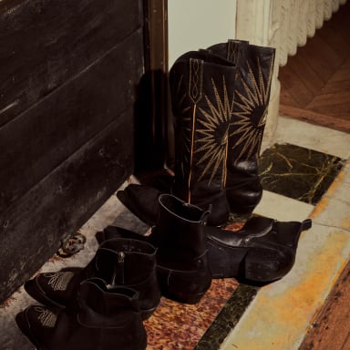 row-of-black-leather-boots-and-ankle-boots-near-a-fireplace
