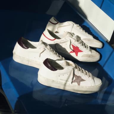 two-pair-of-white-sneakers-with-red-and-glittered-stars-on-a-blue-surface