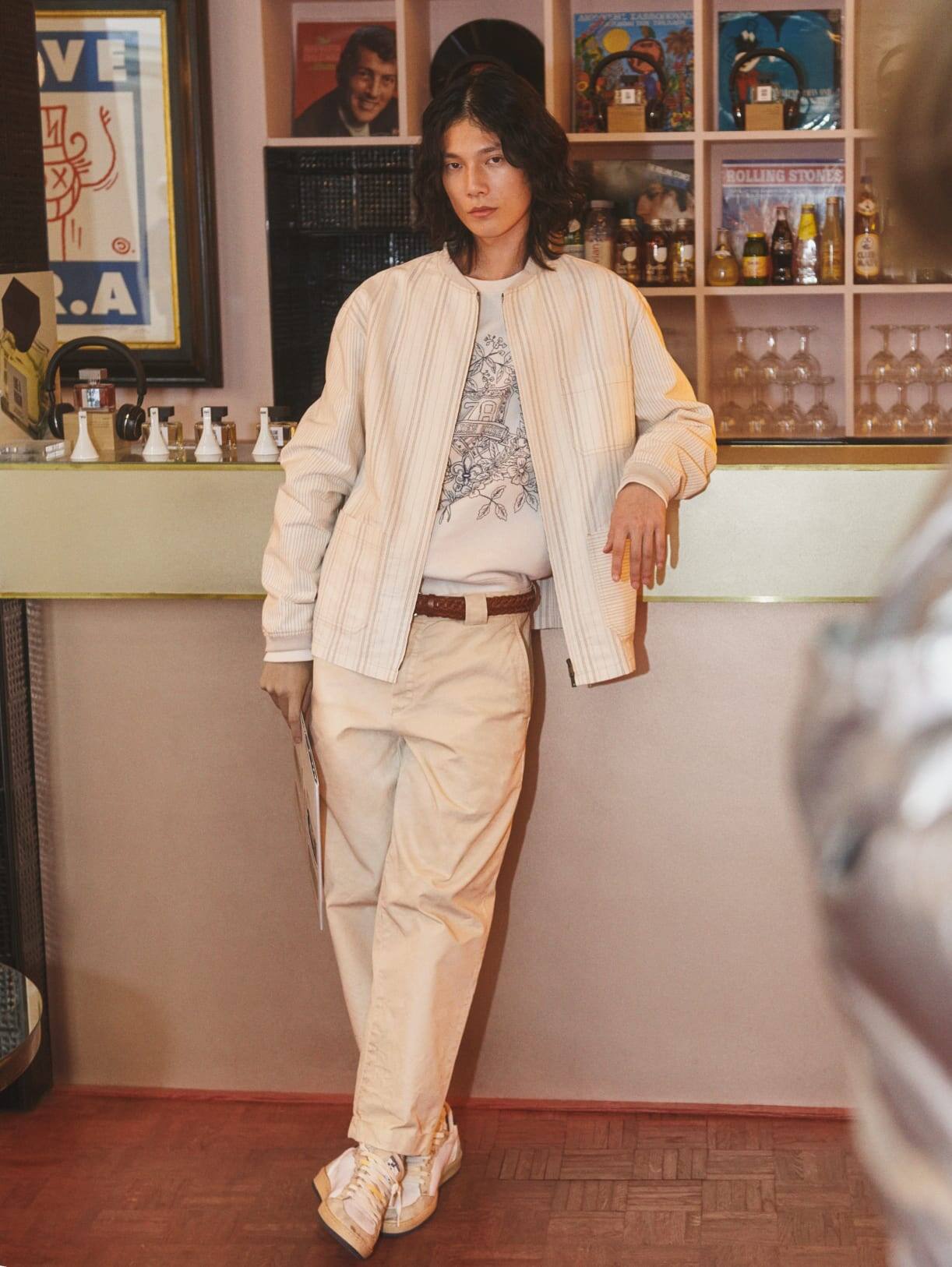 man-wearing-white-and-cream-pants-jumper-and-cardigan-while-leaning-on-bar-counter