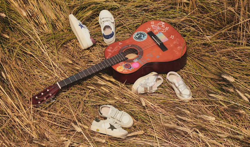 white-super-star-and-old-school-sneakers-with-black-star-on-grey-blanket-on-wooden-floor-with-car-toys