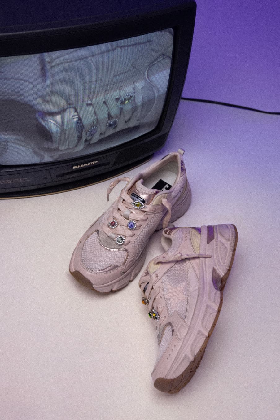 Pink lightstar sneaker with flower details in front of old tv