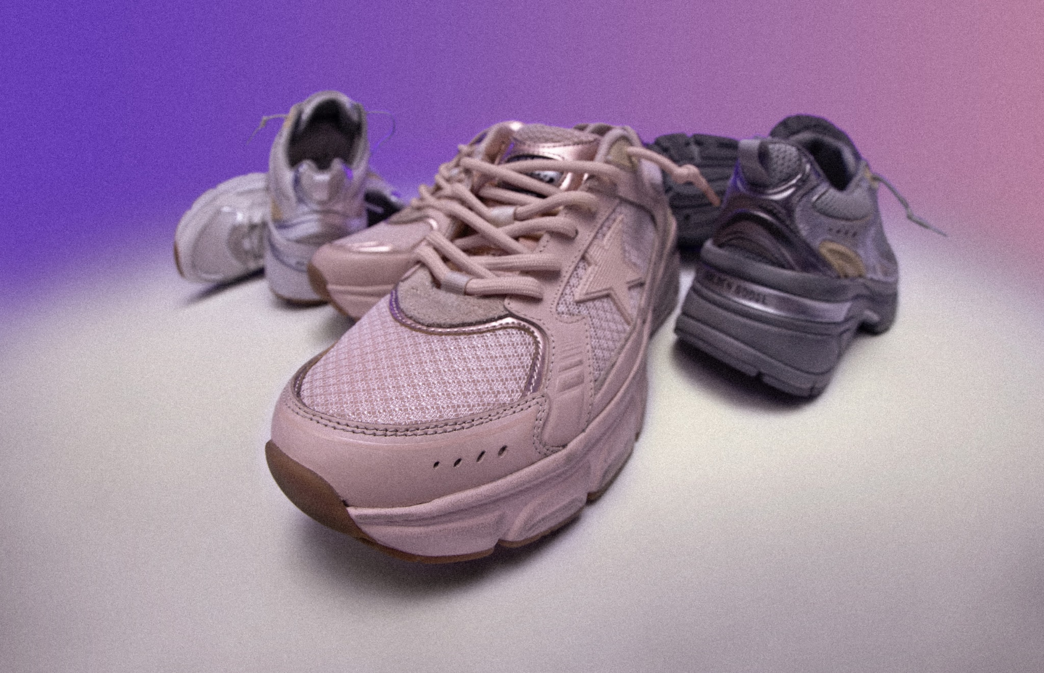 Close up view of pink light star sneakers with other two colorways behind