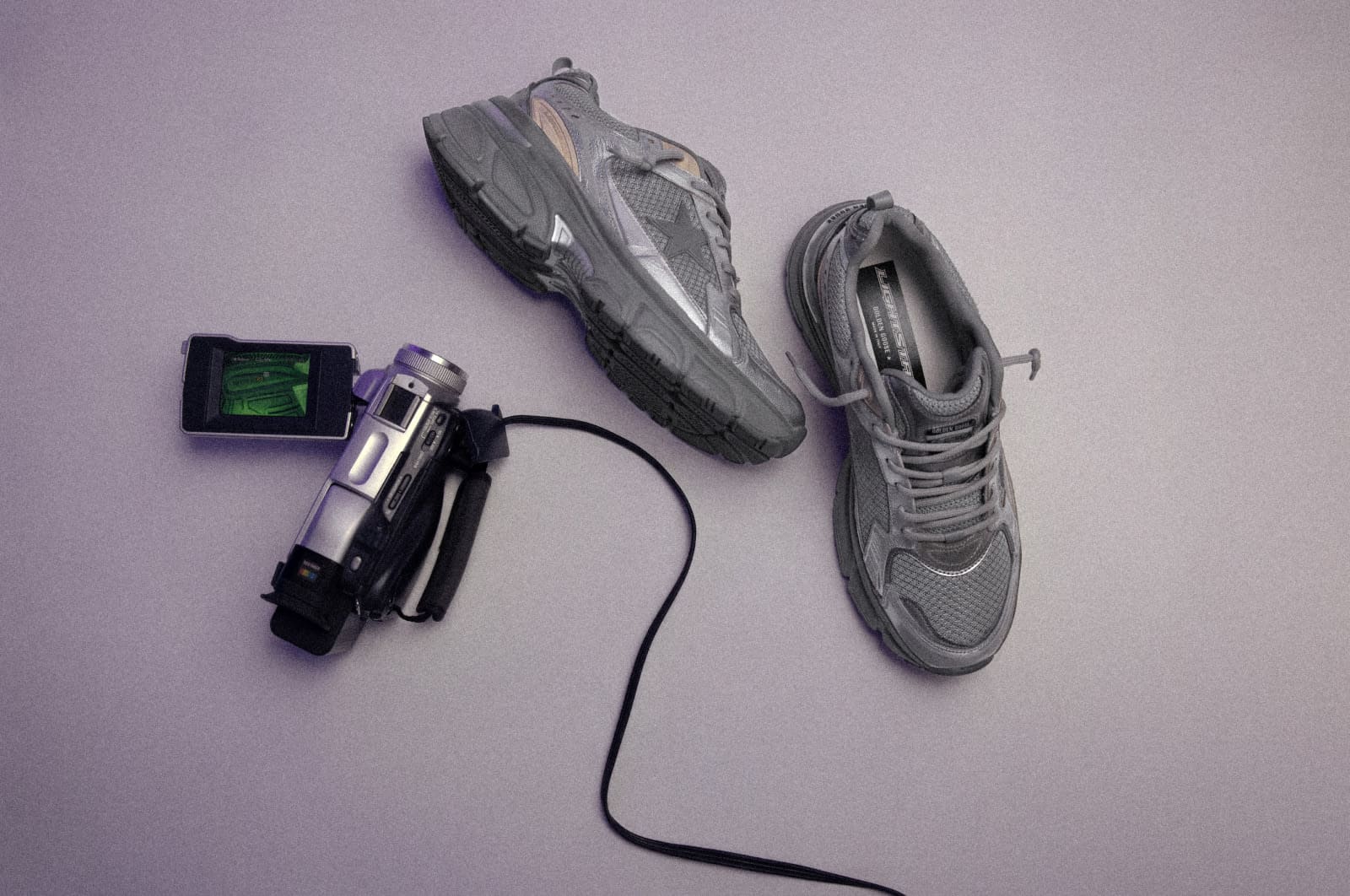 View from above of Silver and grey lightstar sneakers next to video camera and cable