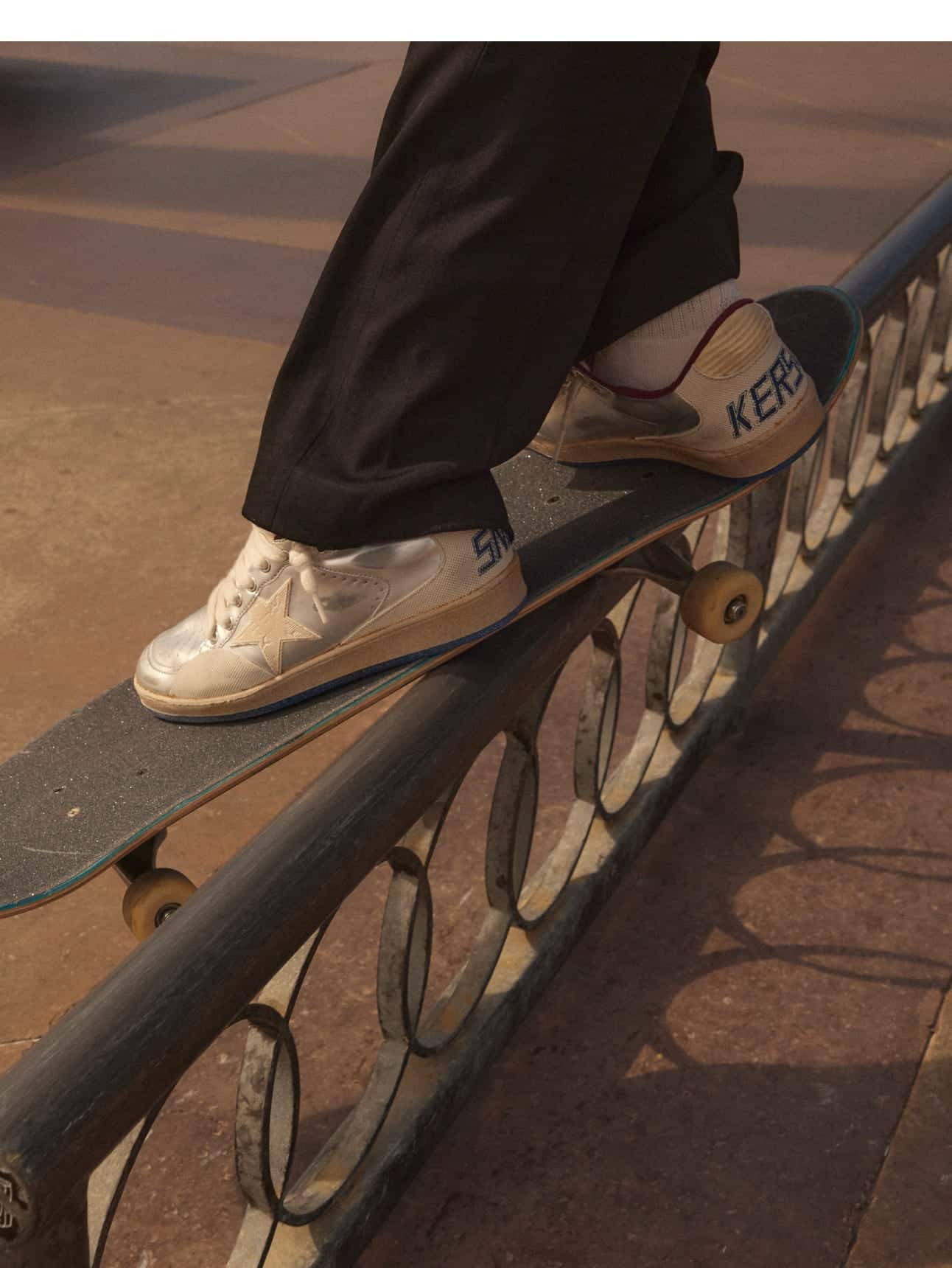 side-view-of-black-pants-and-silver-ball-star-pro-sneakers-on-skatebord-while-stunting-on-a-railing-in-a-skatepark