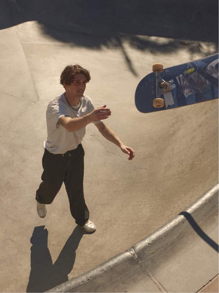 skater-cory-juneau-wearing-white-tshirt-and-black-pants-throwing-skateboard-from-inside-skatepark