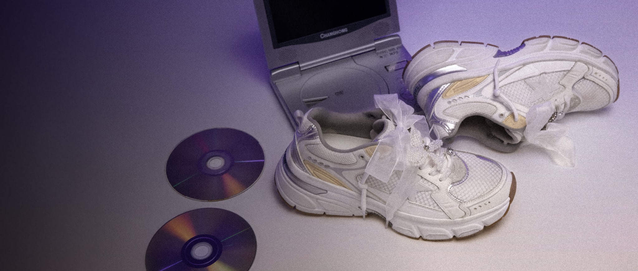 white-sneakers-with-bow-next-to-cds