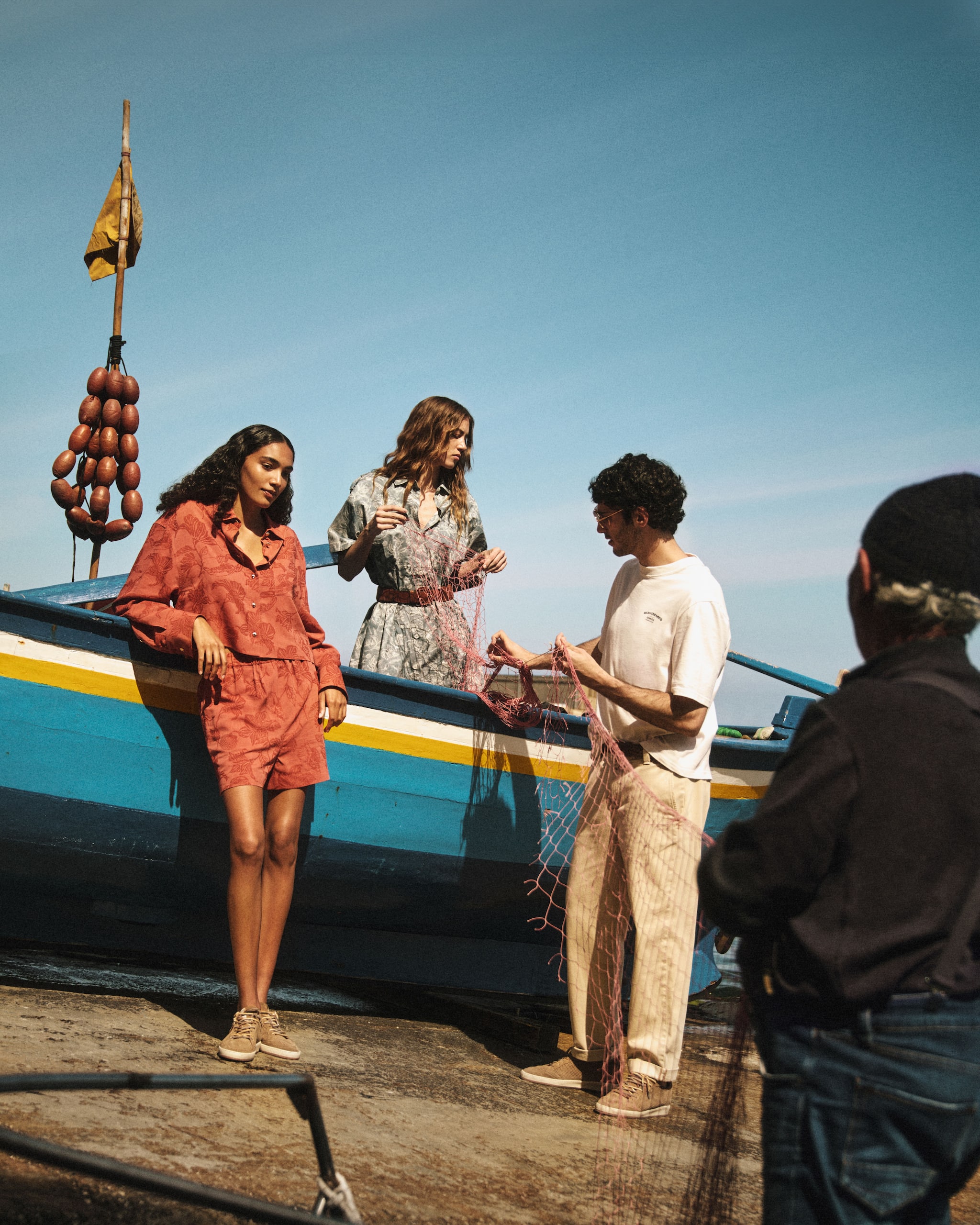 fishermen-and-models-by-blue-yellow-boat-wear-the-resort-collection