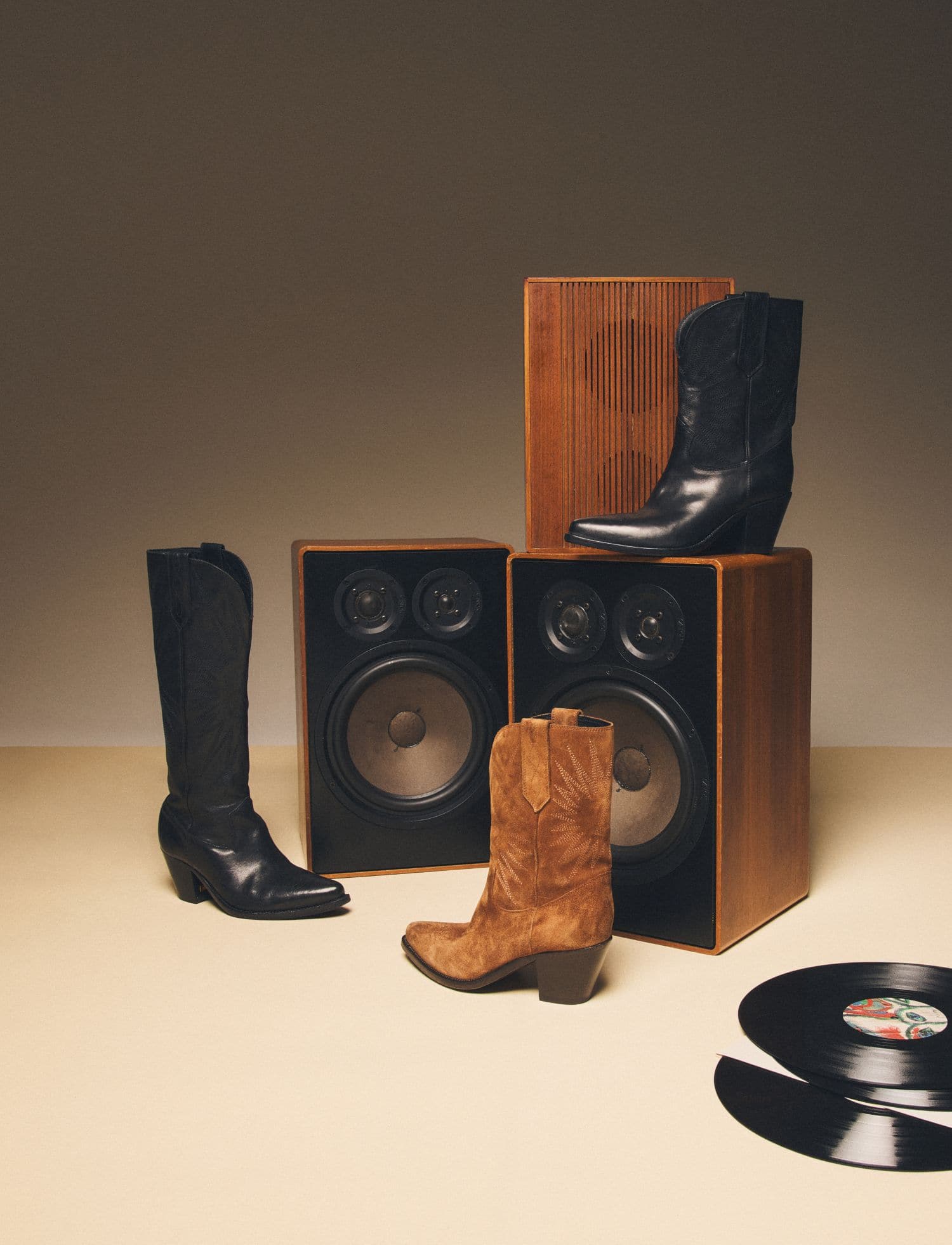 black-and-brown-golden-boots-on a couple-of-speakers