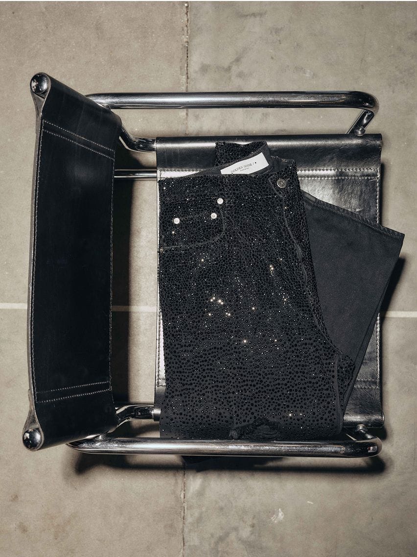 black-denim-pants-with-crystal-and stone-decoration-on-a-black-leather-chair