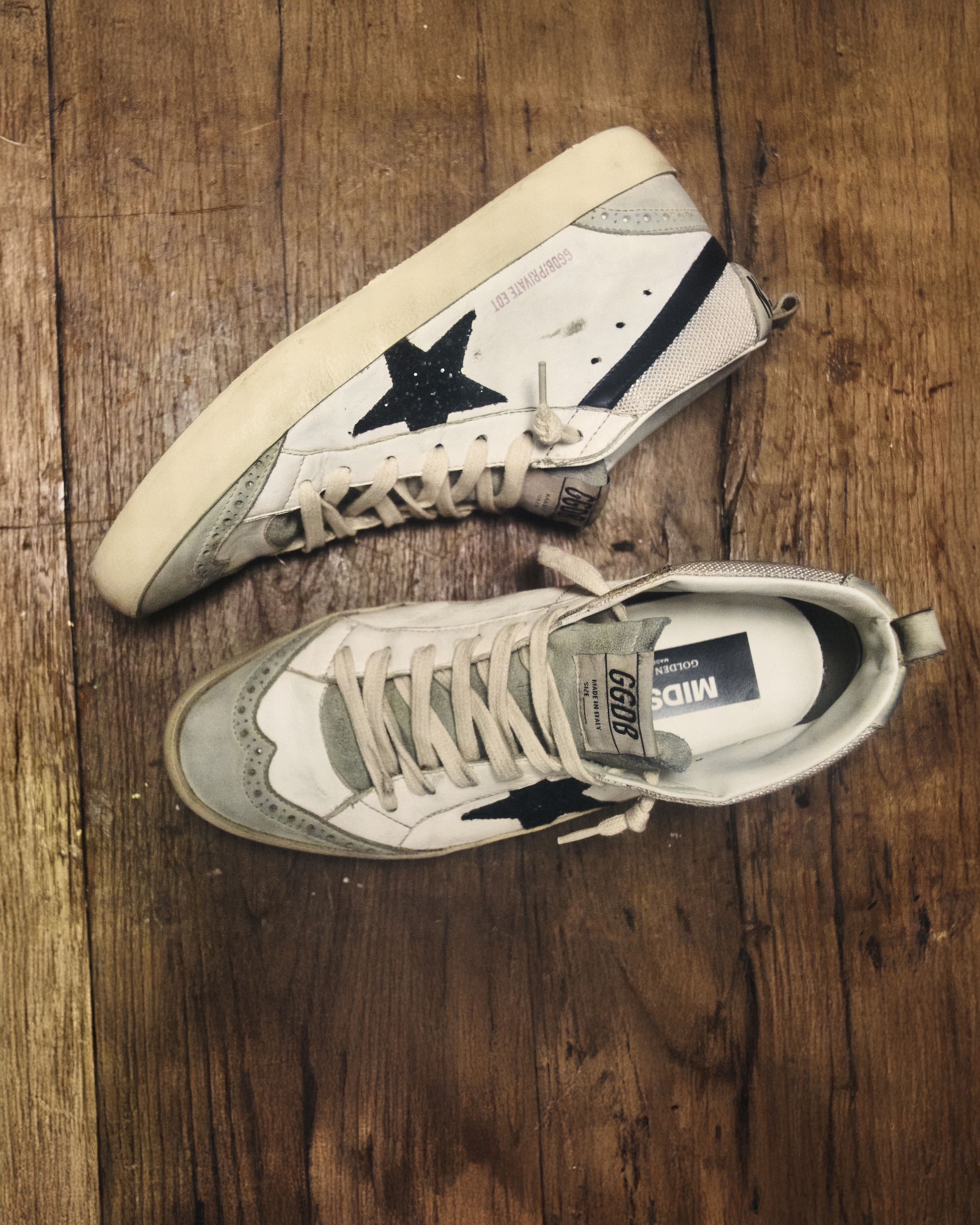 side-view-of-white-ballstar-sneakers-on-moquet-with-red-star-and-details-and-personalized-black-marking-and-red-love-you-text-on-heel-with-shadow-of-a-hand