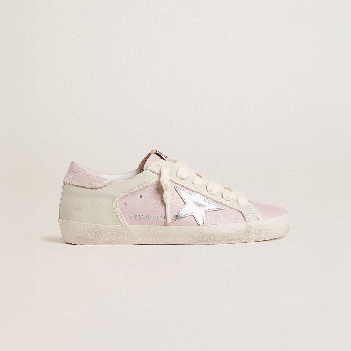 women’s-light-pink-sneaker-with-white-star-and-ivory-suede-details-on-neutral-background