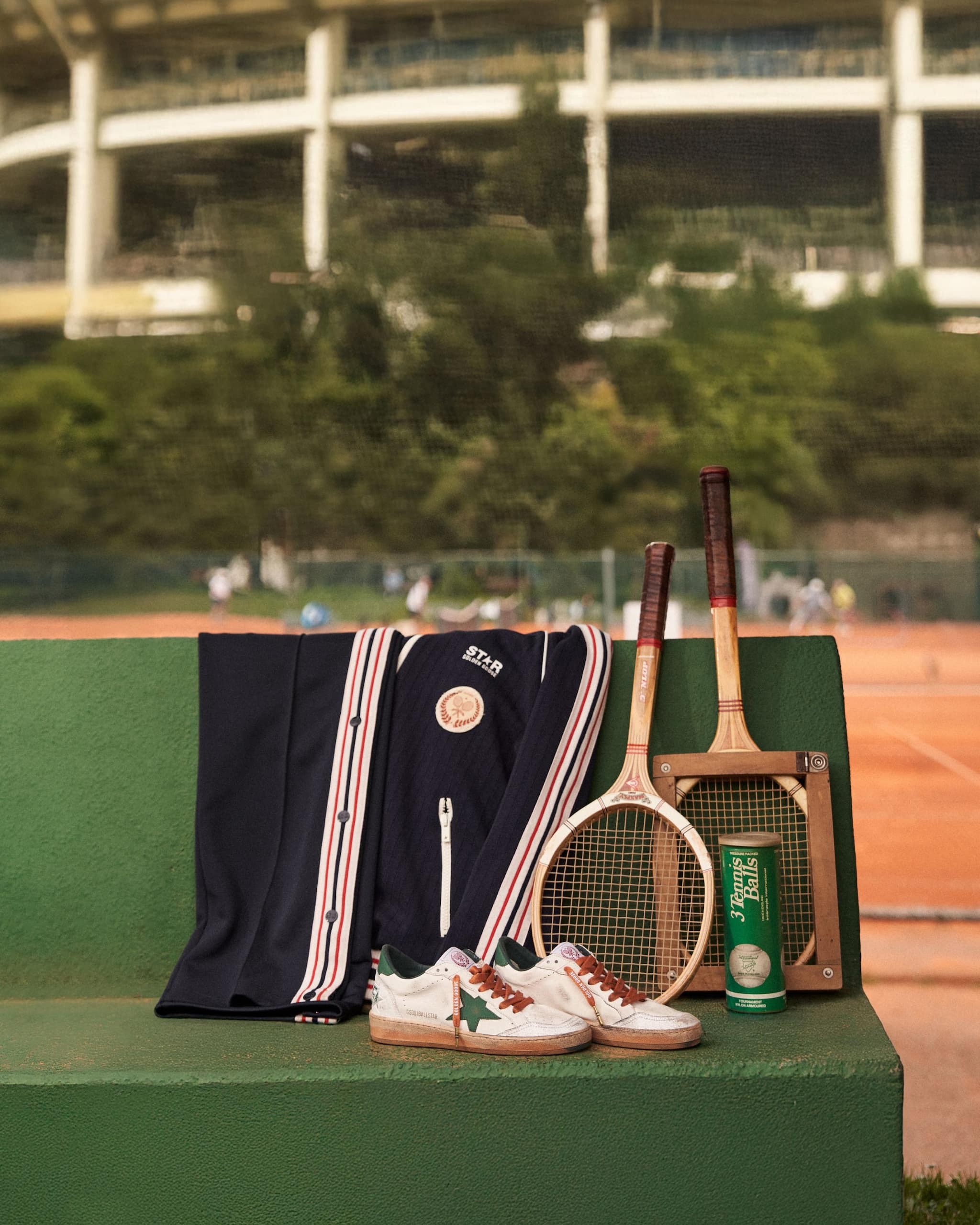 blue-cardigan-and-ballstar-sneakers-on-a-bench-in-front-of-stadium