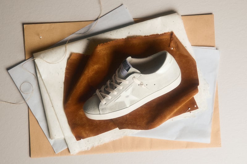 white-sneaker-on-layered-fabric-and-paper-materials-flat-lay