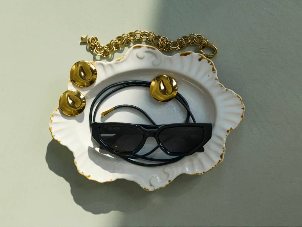 black-sunglasses-and-gold-jewelry-on-a-white-saucer