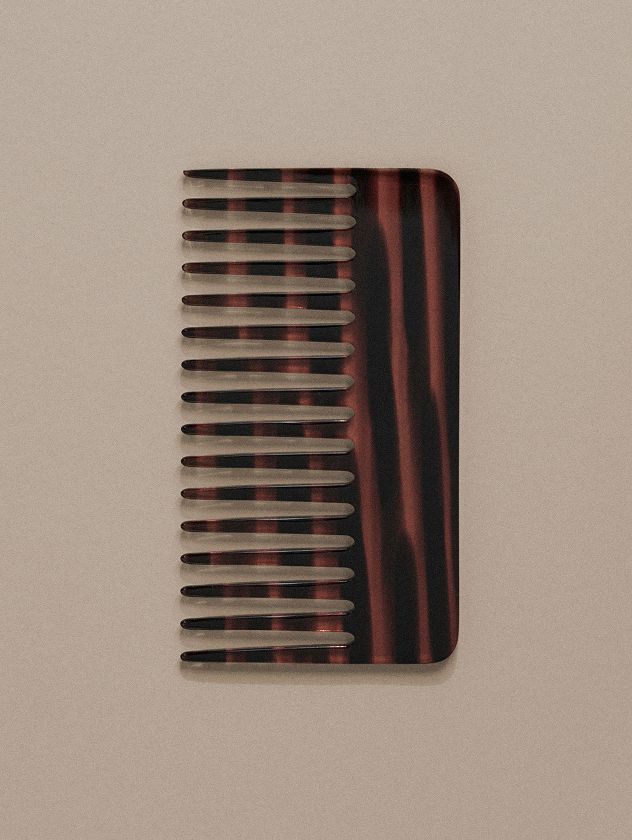 brown-hair-comb-on-a-light-green-background
