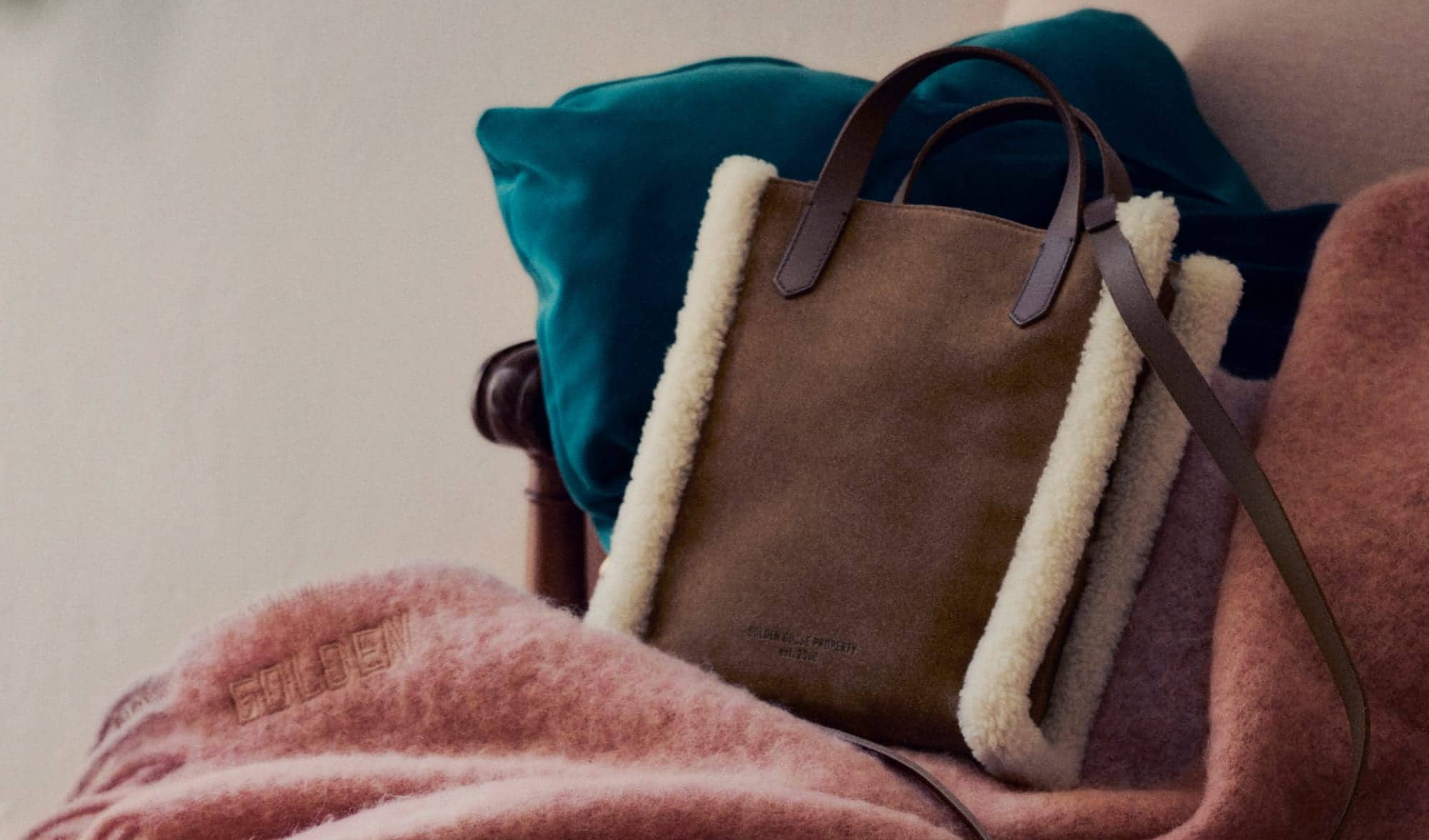 brown-California-bag-mini-with-white-shearling-trim-features-on-pink-scarf-and-blue-cushion