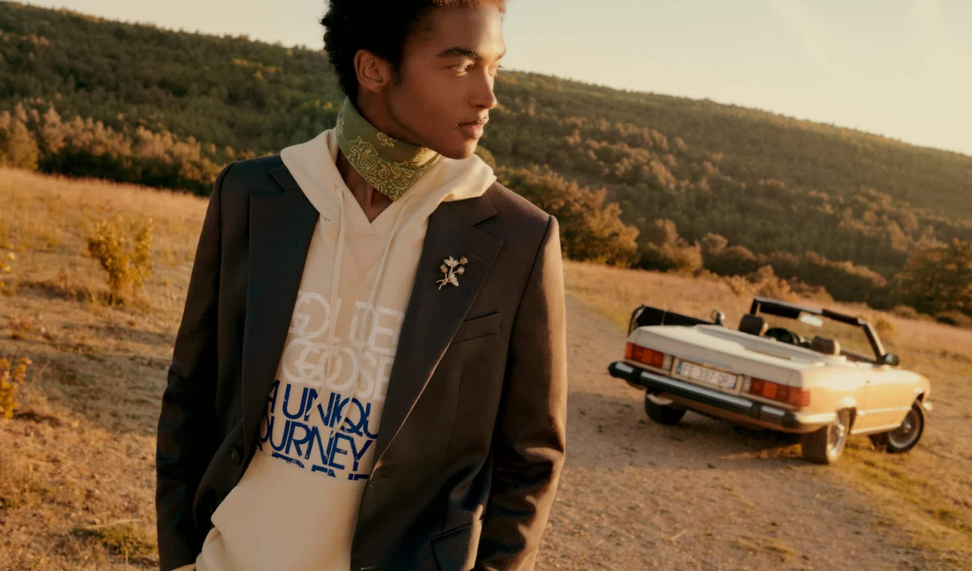 boy-in-front-of-his-car-in-a-rural-landscape-wearing-a-Marzipan-colored-sweatshirt-with-writing-on-the-front