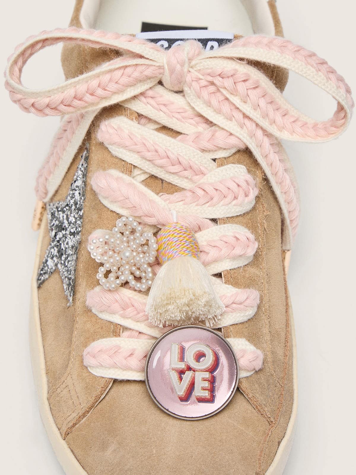 Lacets Skins beige clair avec tressages roses, broche et application
