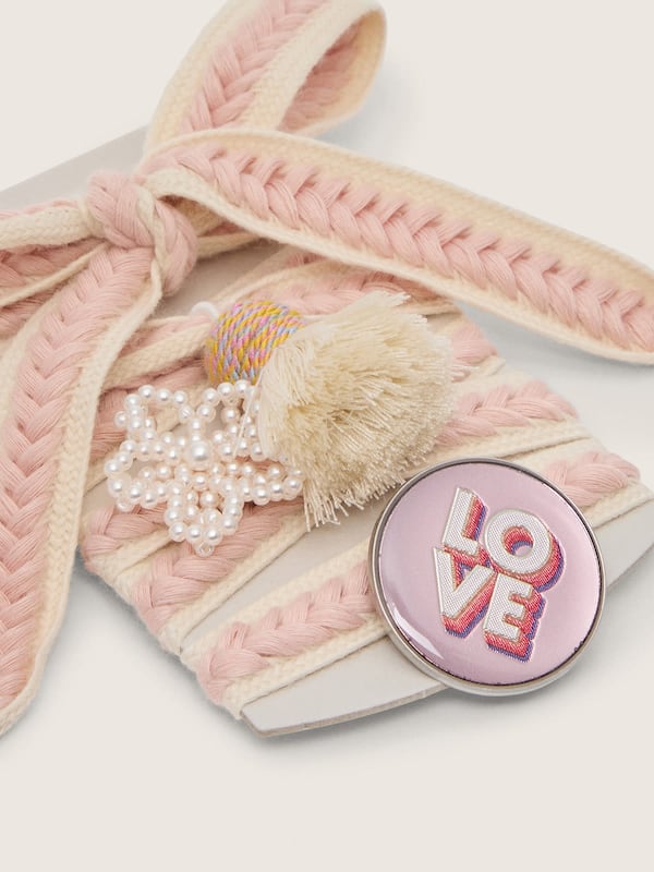Skins laccio beige chiaro con intrecci rosa, spilla e applicazioni